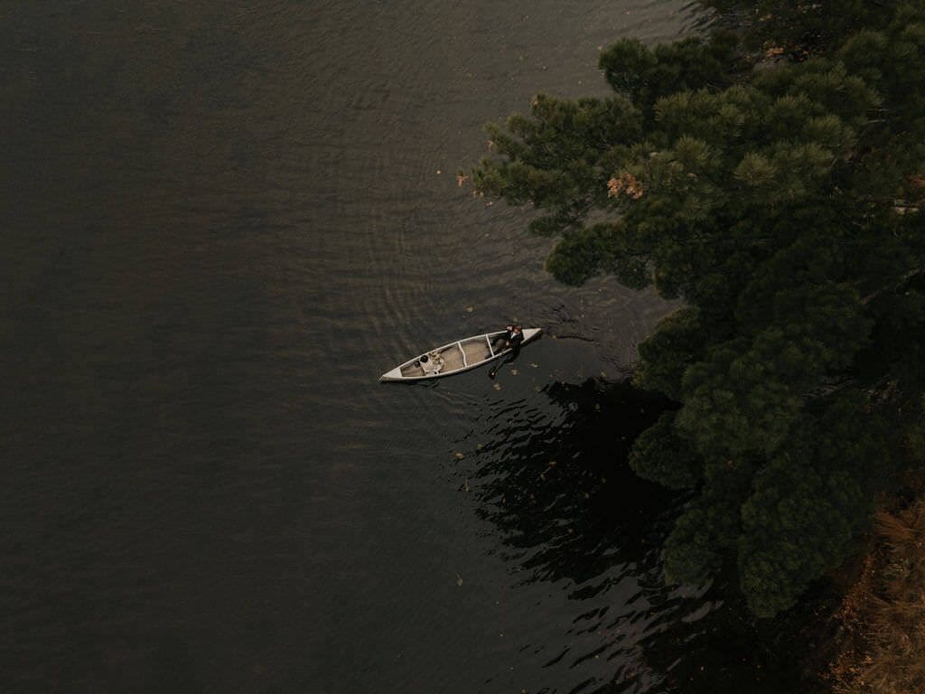 A small boat on calm water near a dense tree line.