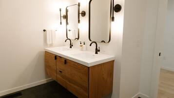A modern bathroom with a white vanity, two mirrors, and a wooden cabinet.