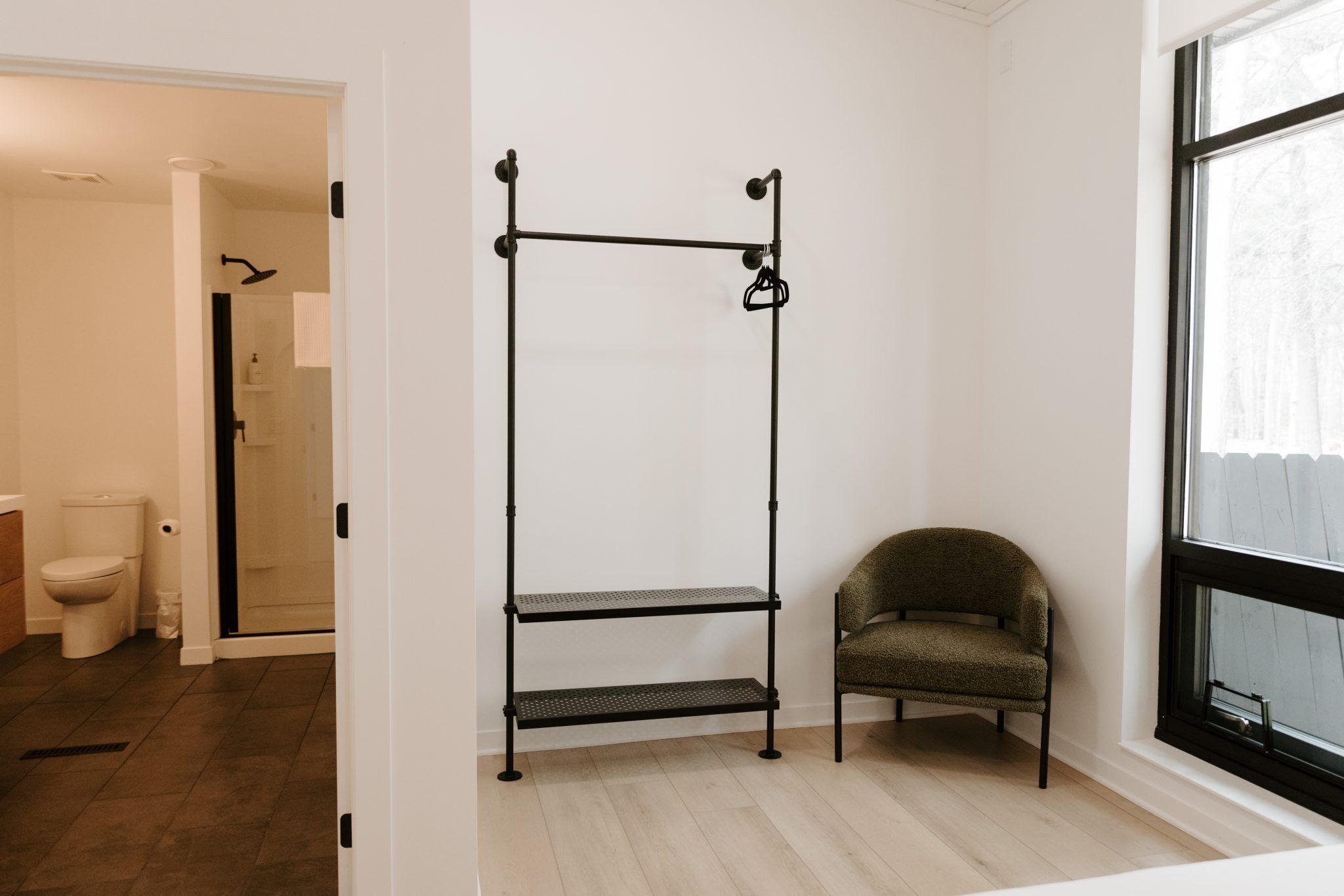 Une salle de bain équipée de toilettes, d’une douche et d’une étagère en métal.