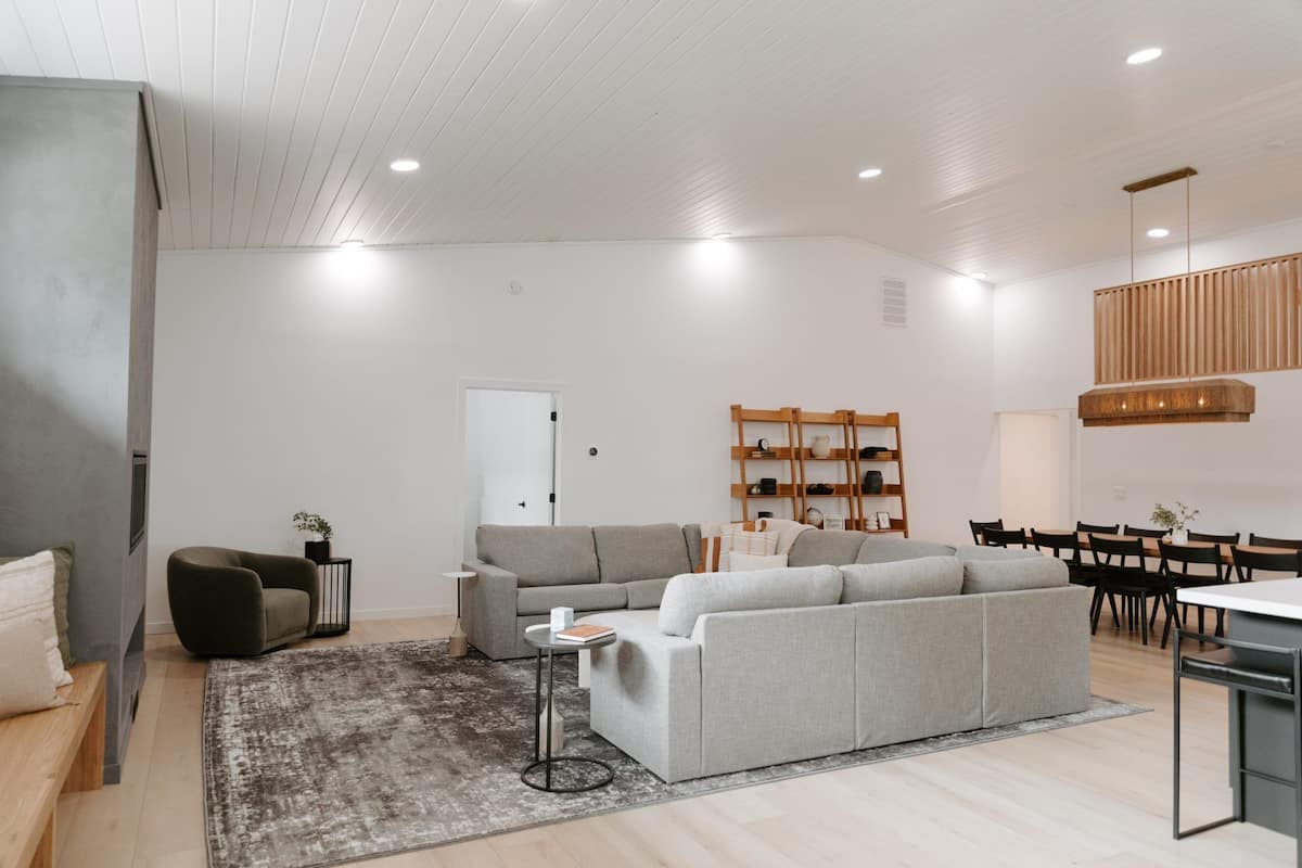 A modern living room with a grey sofa, a small round table, and a grey rug.