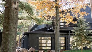 A modern house with a garage, surrounded by large trees and a well-maintained lawn. - Nature Link Resort (Nisswa)