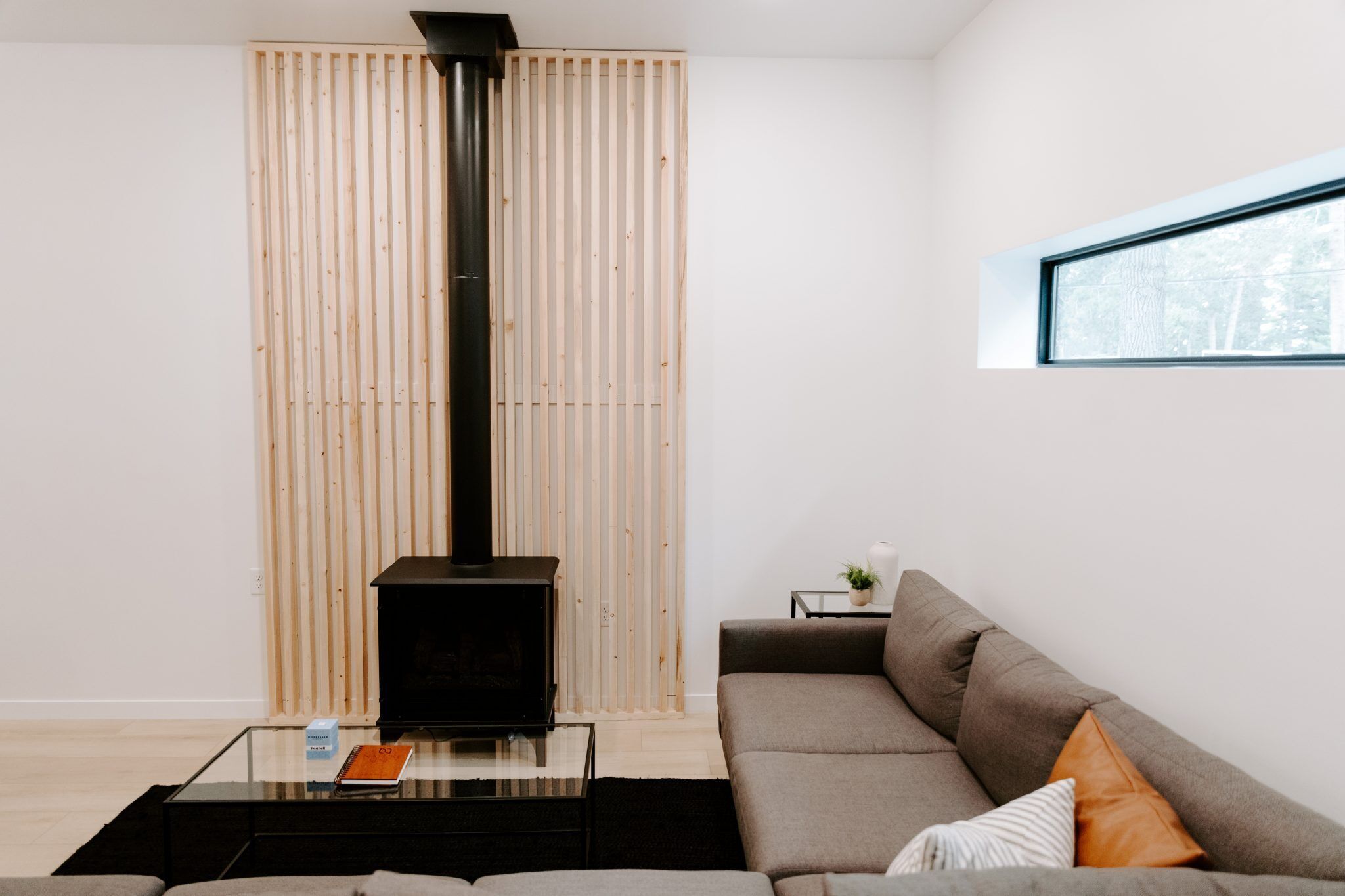 A modern living room with a sofa, a coffee table, a black fireplace, and a window.
