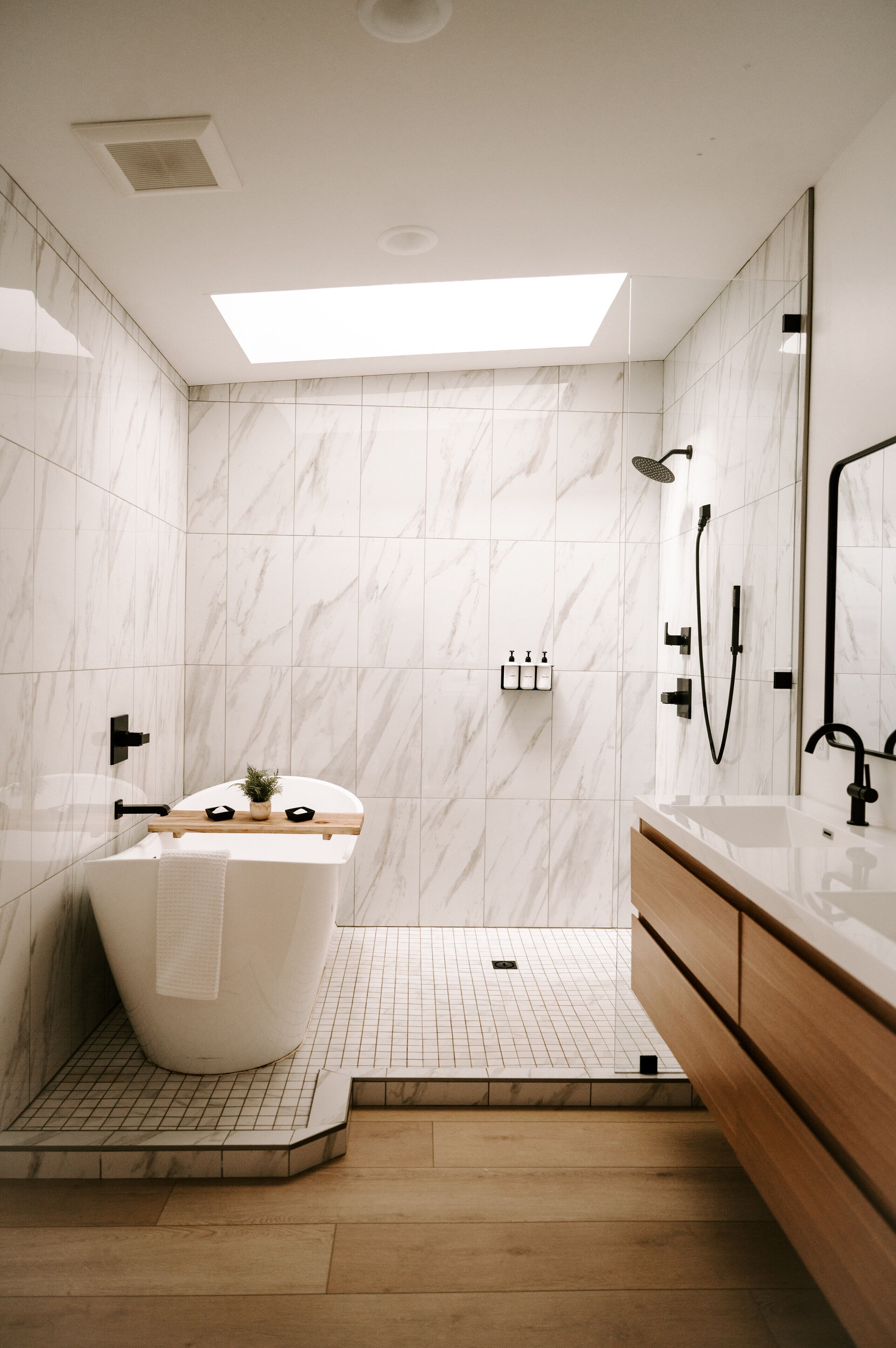 A modern bathroom with a freestanding bathtub, a shower area, and a vanity with a mirror.