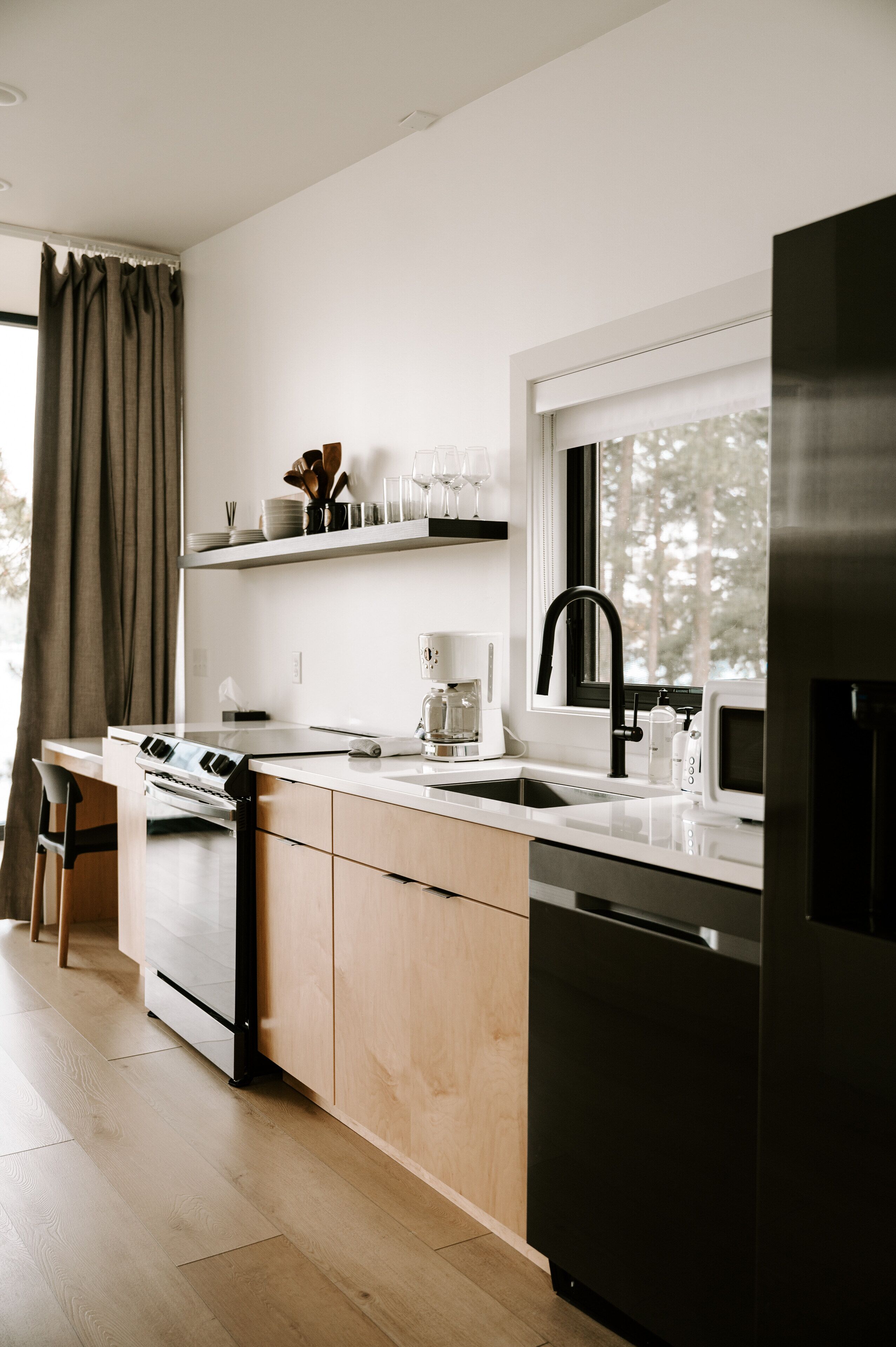 Una cocina moderna con horno empotrado, lavavajillas y refrigerador de acero inoxidable.