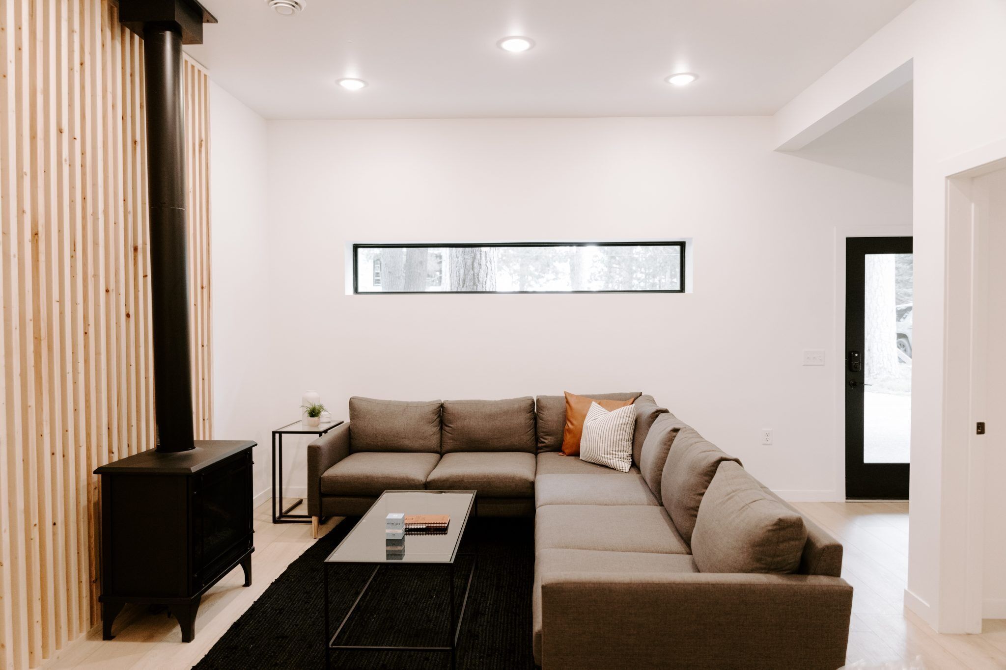 A modern living room with a sectional sofa, a small side table, a black coffee table, and a black fireplace.