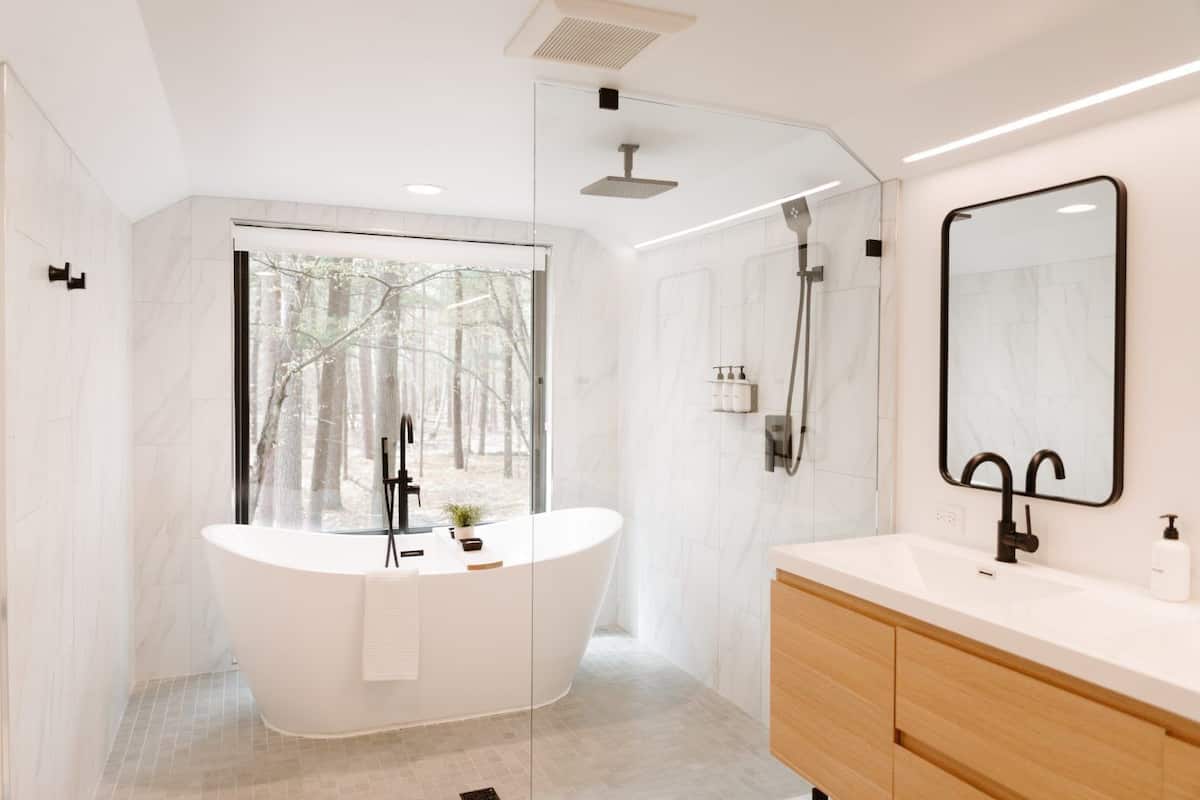 A modern bathroom with a freestanding bathtub, a shower, a large mirror, and a vanity with a sink.