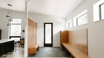 A modern interior with a long bench, a wooden partition, and a kitchen area with a counter and stools.