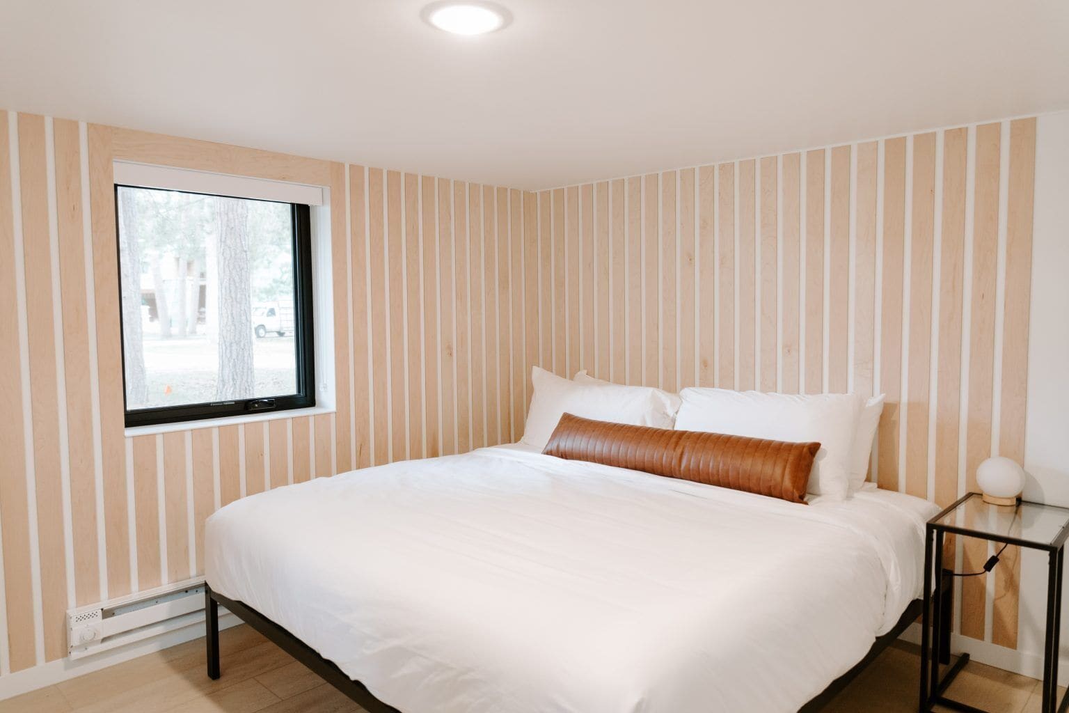 Un dormitorio con una cama grande, una ventana y una mesita de noche con una lámpara.