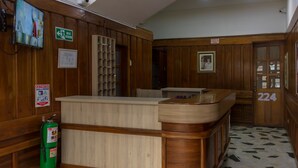 A reception area with a wooden counter, a fire extinguisher, and a door marked with the number 224. - Ayenda Maraná (Manizales)