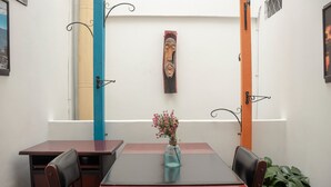 A dining area with a table, chairs, a vase with flowers, and a wall with a decorative piece. - Ayenda Maraná (Manizales)