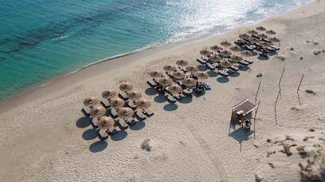 On the beach, white sand, sun-loungers, beach umbrellas. Sundunes Hotel Naxos