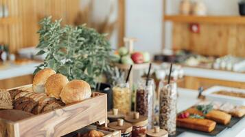 Un bufé con diversos alimentos, como pan, pasteles y frascos con pastas y untables.