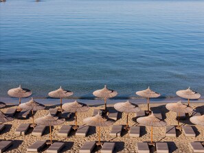 A beach with rows of sun loungers and thatched umbrellas. - Sundunes Hotel Naxos  (Naxos)
