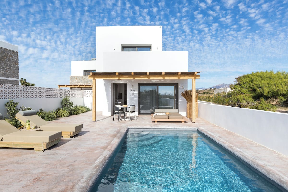 A modern villa with a swimming pool, outdoor seating, and a mountain view.