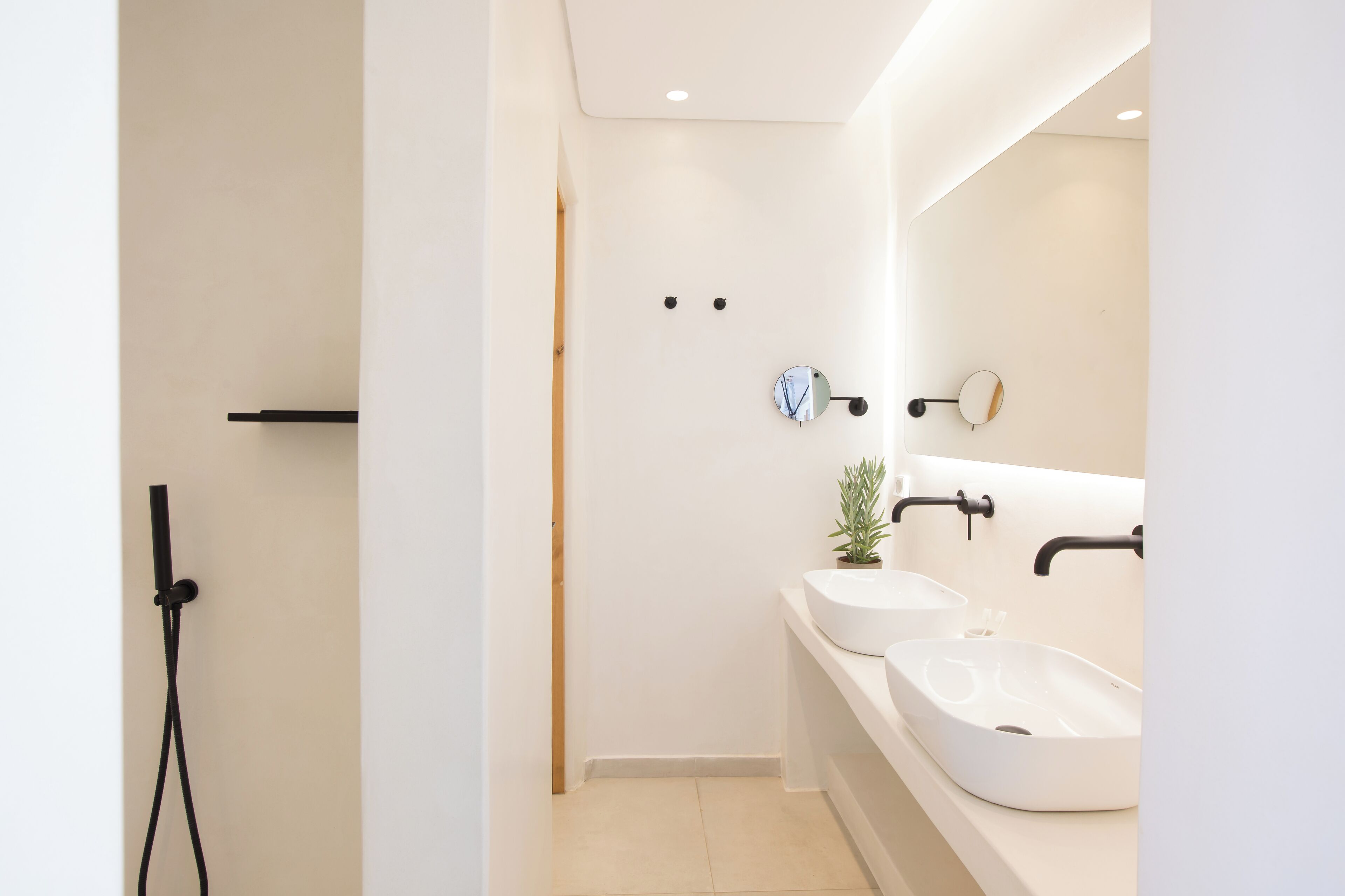 A modern bathroom with two sinks, a mirror, and a shower.