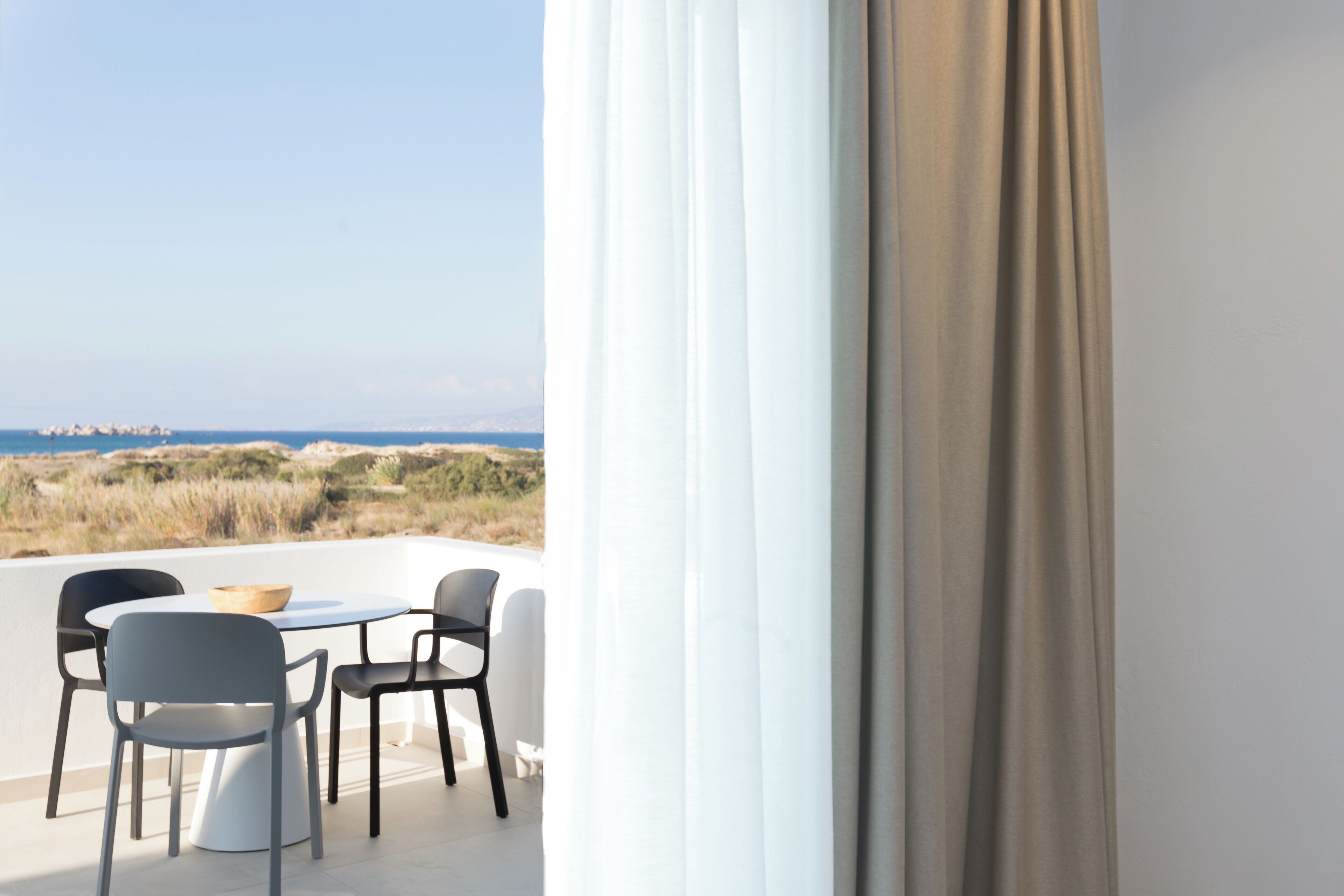 Un balcone con tavolo e sedie, con vista sul paesaggio costiero.