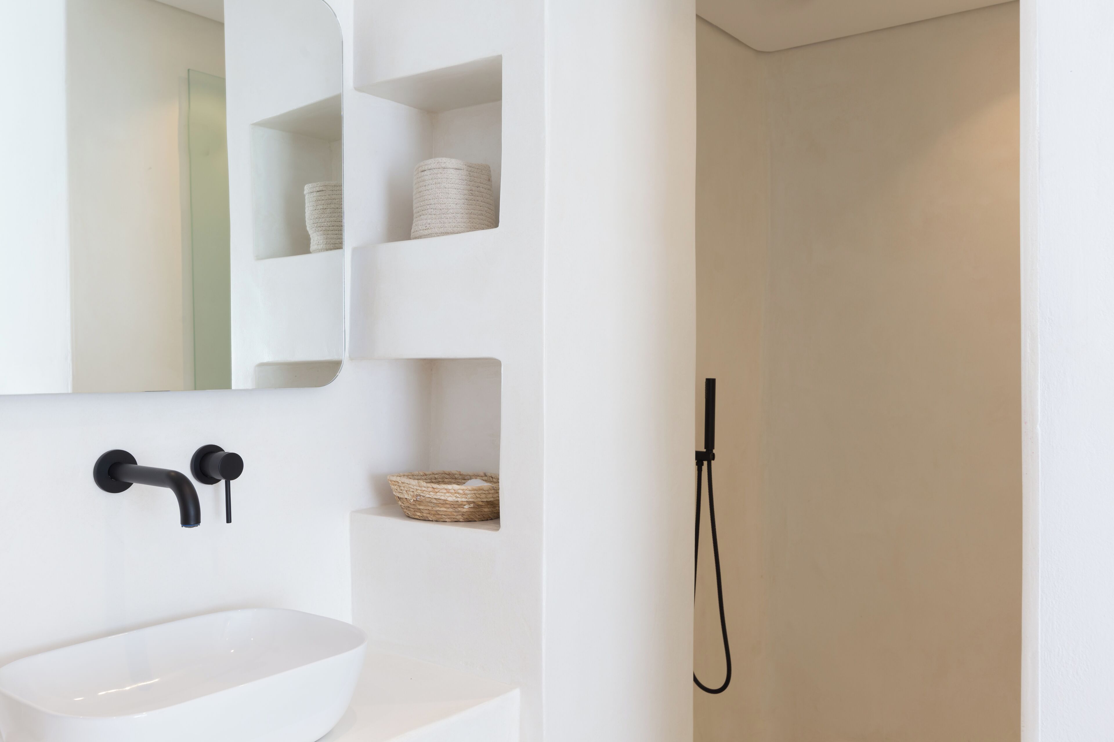 A bathroom with a white sink, a mirror, and a shower.