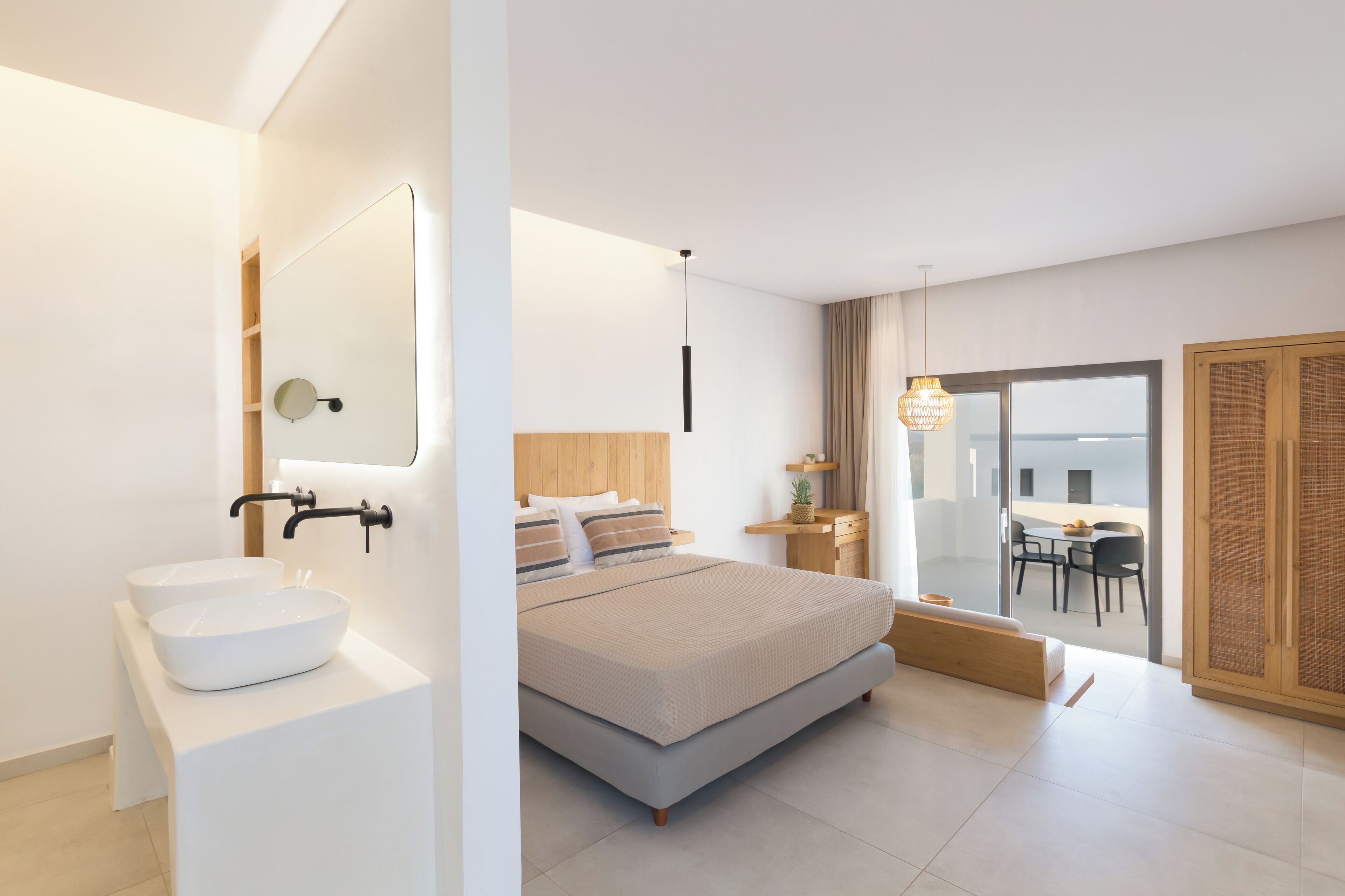 Ein modernes Schlafzimmer mit einem großen Bett, einem weißen Waschbecken und einem großen Fenster mit Blick auf die Stadt.
