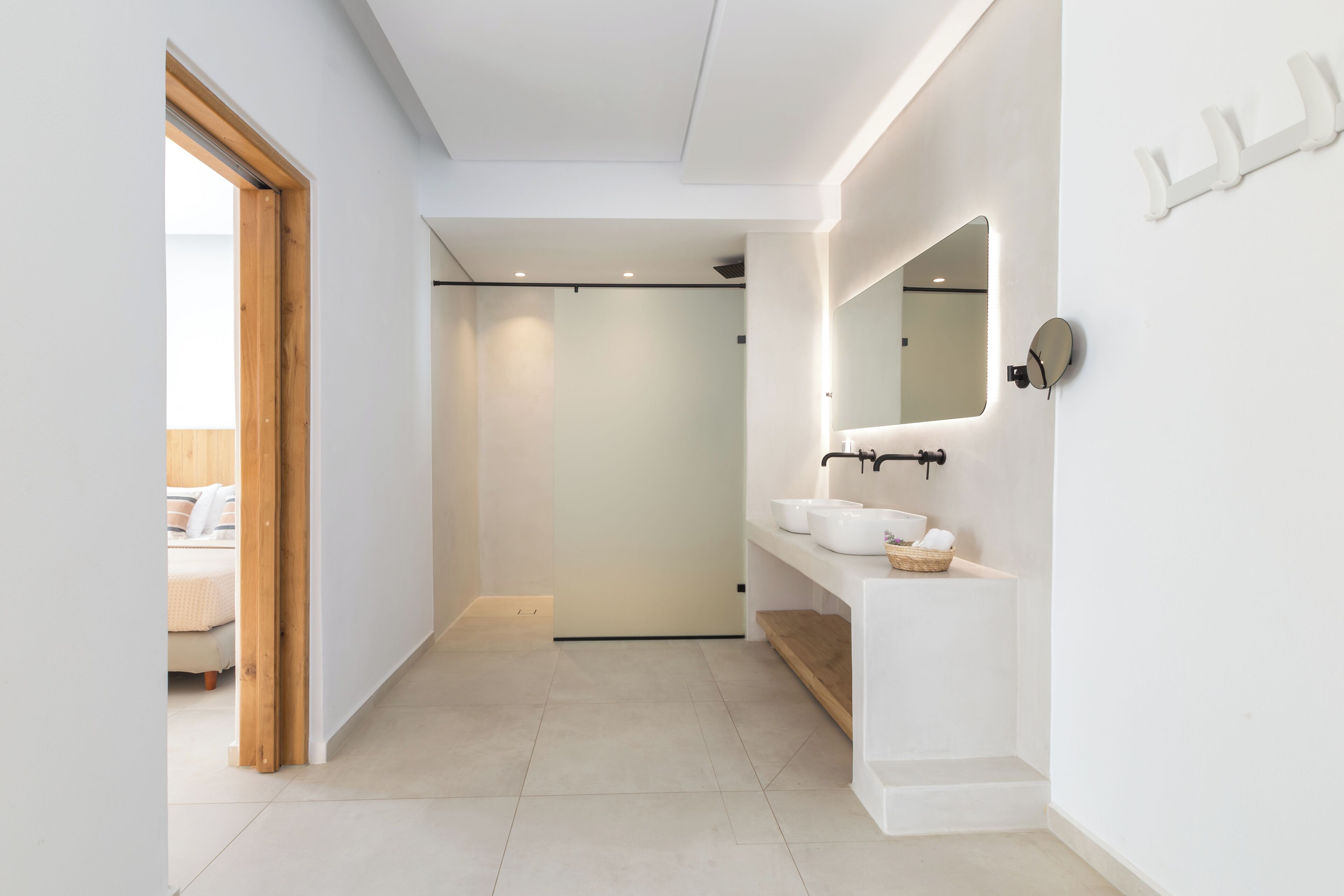 A modern bathroom with a white sink, mirror, and shelves.