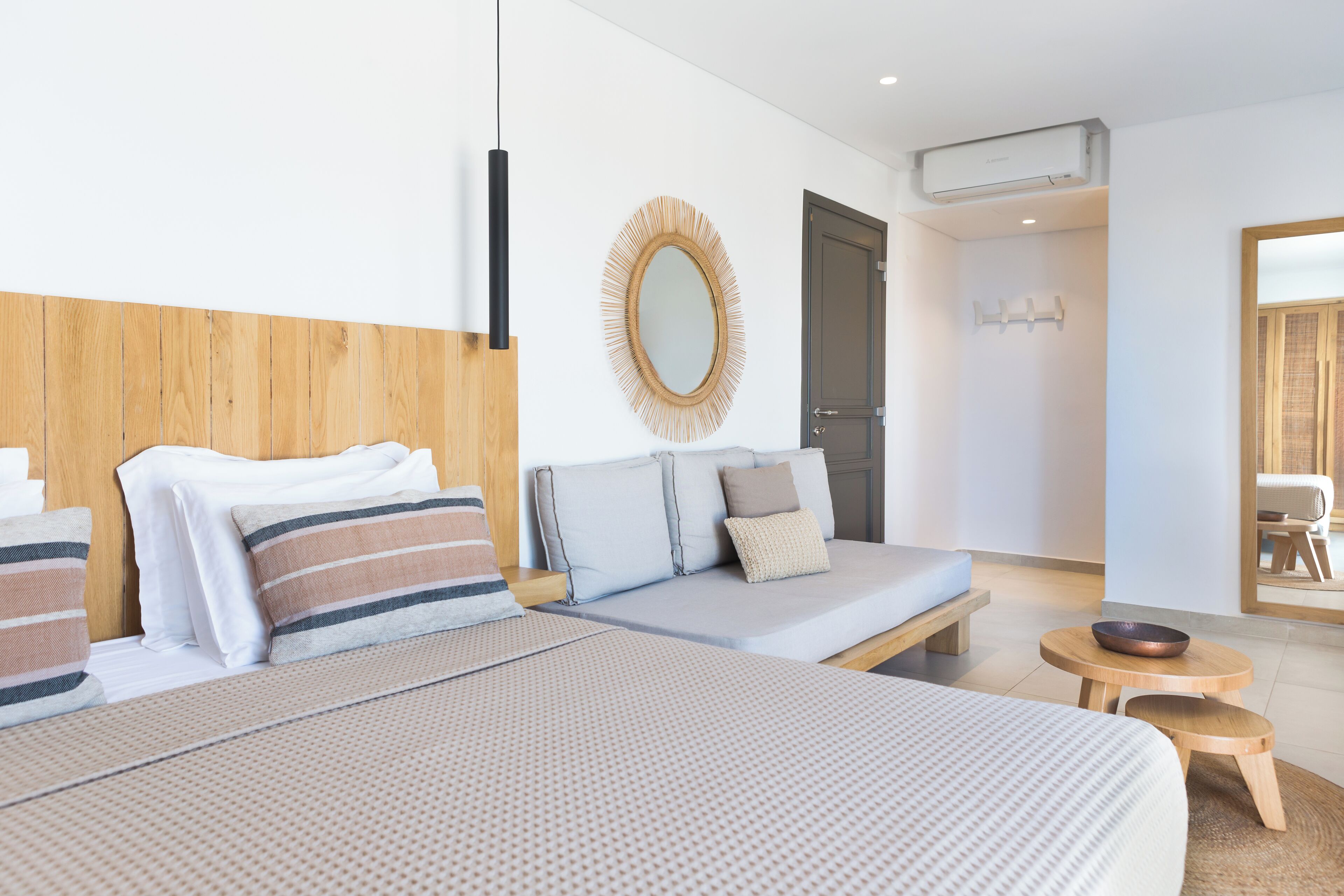 Ein modernes Hotelzimmer mit einem großen Bett, einer Couch, einem kleinen runden Tisch und einem Spiegel an der Wand.