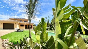 Une maison avec une piscine, un patio couvert et une pelouse bien entretenue.