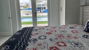 A bedroom with a bed, a view of a swimming pool, and a door leading outside. - Relaxing home in a beautiful location with luxurious accommodations (Key Largo)