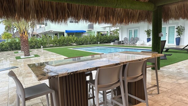 An outdoor bar area with a pool, surrounded by greenery and a thatched roof. - Relaxing home in a beautiful location with luxurious accommodations (Key Largo)