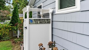 A house with a sign that reads "SHOWERS $1 TO WATCH $2" and a white porch with a wooden railing. - Reserve Fall 2026! Beach House in the Pier W/ POOL, short walk to the beach! (Narragansett)