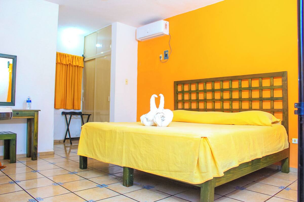 A room with a bed, a desk, a chair, and an air conditioning unit.