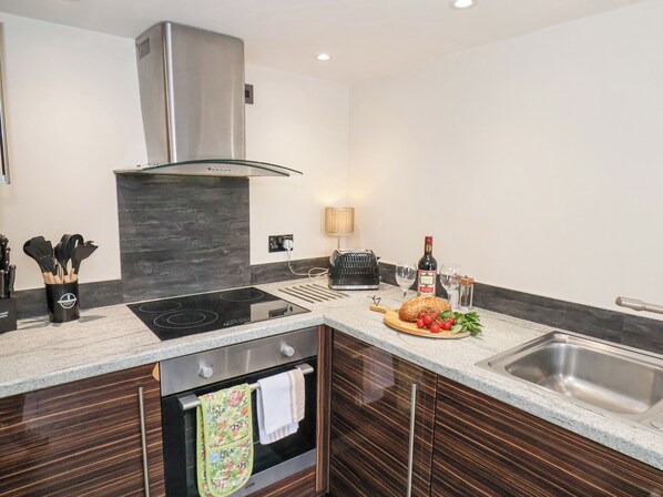 A modern kitchen with a built-in oven, a stainless steel range hood, and a granite countertop. - The Nail Shed (Scarborough)