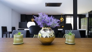 A dining table with a decorative vase in the center, flanked by two smaller vases.