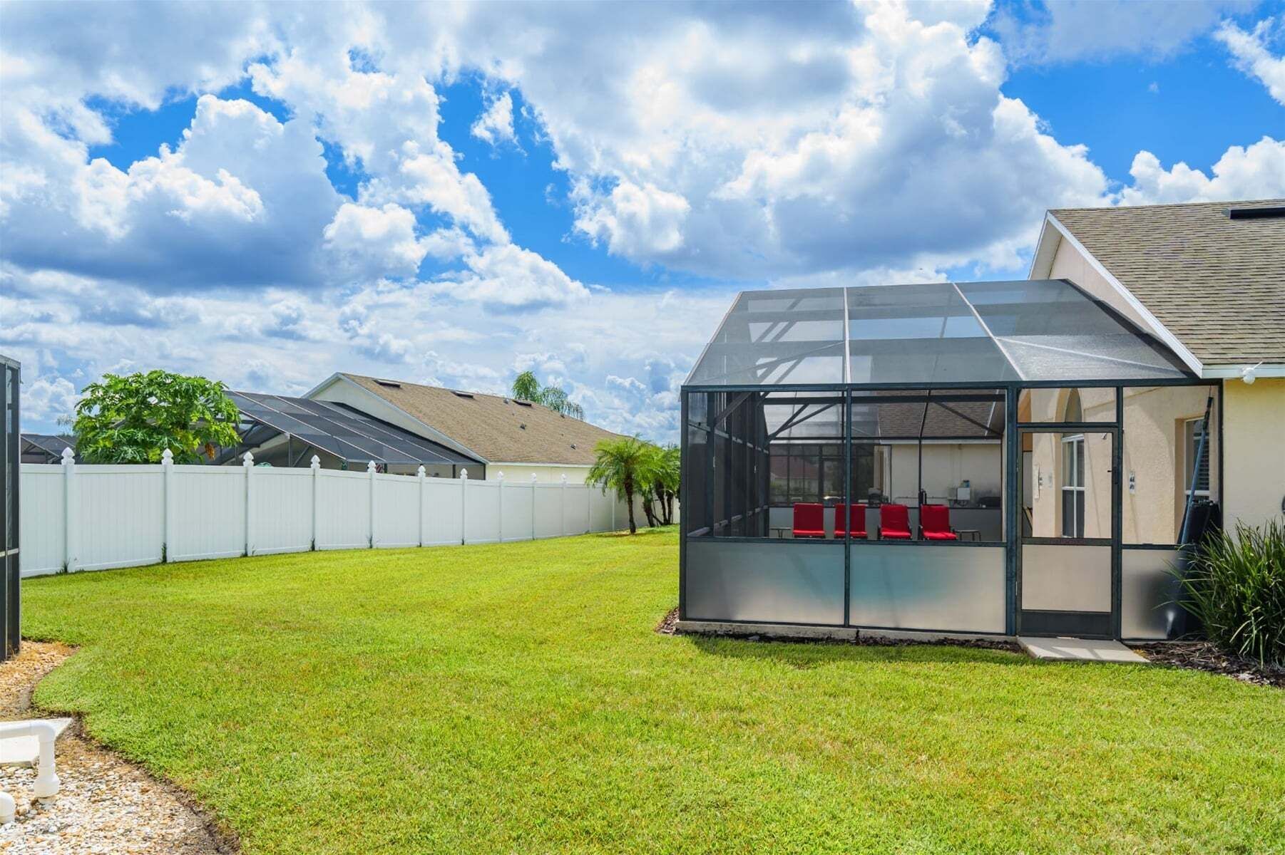 Une maison dotée d’un patio entièrement vitré, de panneaux solaires et d’une clôture blanche.