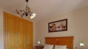 A bedroom with a large bed, wooden wardrobe, two bedside tables with lamps, and a painting on the wall. - TERRASOL AZUCARERA 3 DORMITORIOS (Torre del Mar)
