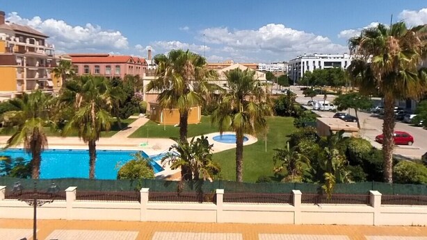 A pool area with palm trees and a clear blue sky. - TERRASOL AZUCARERA 3 DORMITORIOS (Torre del Mar)