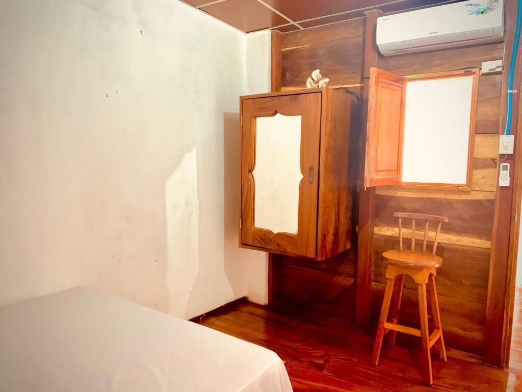 A room with a bed, wooden wardrobe, and a chair.