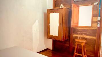 A room with a bed, wooden wardrobe, and a chair.