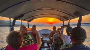 Un bateau transportant des passagers qui prennent des photos du coucher de soleil.
