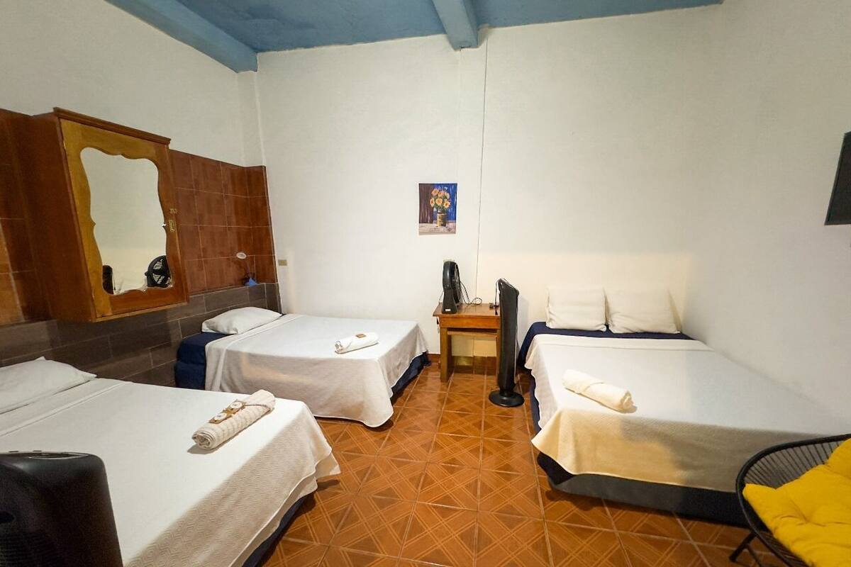 Une chambre d’hôtel avec deux lits simples, un bureau, une chaise, une télévision et un miroir au mur.
