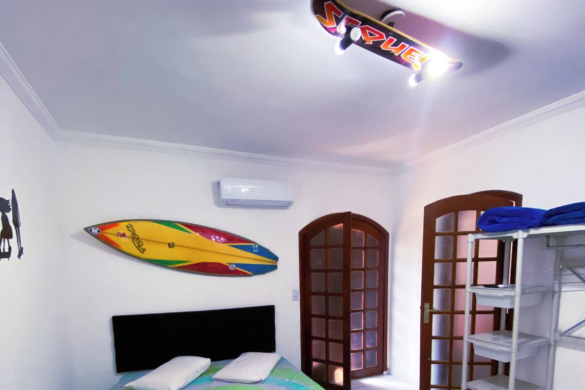 A bedroom with a bed, a surfboard, a wardrobe, and a door.