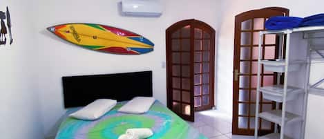 Een slaapkamer met een bed, een surfboard, een kast en een deur.