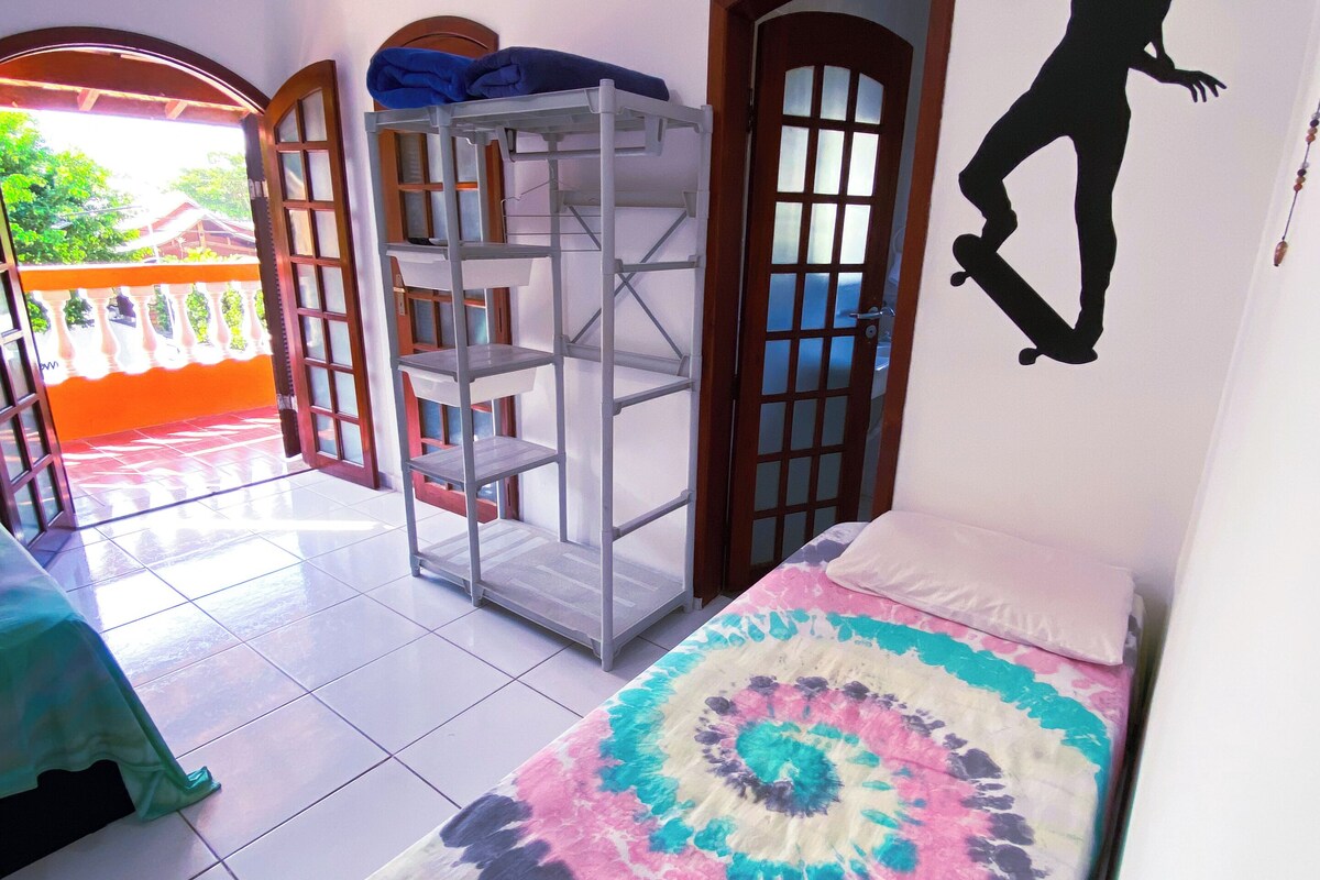 Un dormitorio con una litera, una colcha de tonos vibrantes, un ventilador de techo y vistas al exterior.