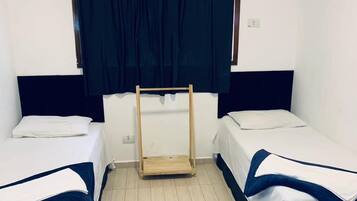 A hotel room with two beds, a wooden ladder, a white air conditioner, and dark curtains.