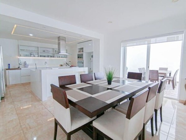 Relax in this open-plan living space with a central dining area and kitchen, perfect for socializing and cooking.