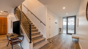 Un interior moderno con una escalera de madera, un televisor de pantalla plana sobre una mesa de madera y un banco.