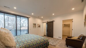 Un dormitorio con una cama grande, un sofá, una puerta corrediza y vistas al exterior.