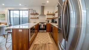 Una cocina moderna con armarios de madera, un refrigerador de acero inoxidable y un horno empotrado.