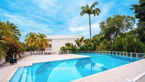 A rectangular swimming pool with a white deck, surrounded by palm trees and tropical plants. - T2 de Charme, Résidence Avec Piscine à 500m de la Plage du Diamant (Le Diamant)