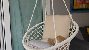 A white macrame hanging chair with cushions, positioned in front of a window with a green curtain. - T2 de Charme, Résidence Avec Piscine à 500m de la Plage du Diamant (Le Diamant)