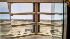 Un interior moderno con un amplio ventanal, una lámpara de techo circular y vistas a una obra en construcción al aire libre.