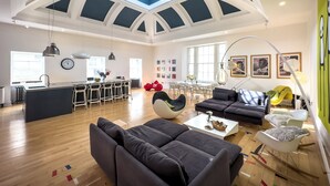 Amplia sala de estar con techo alto, una isla central con asientos y un comedor con vista al cielo.